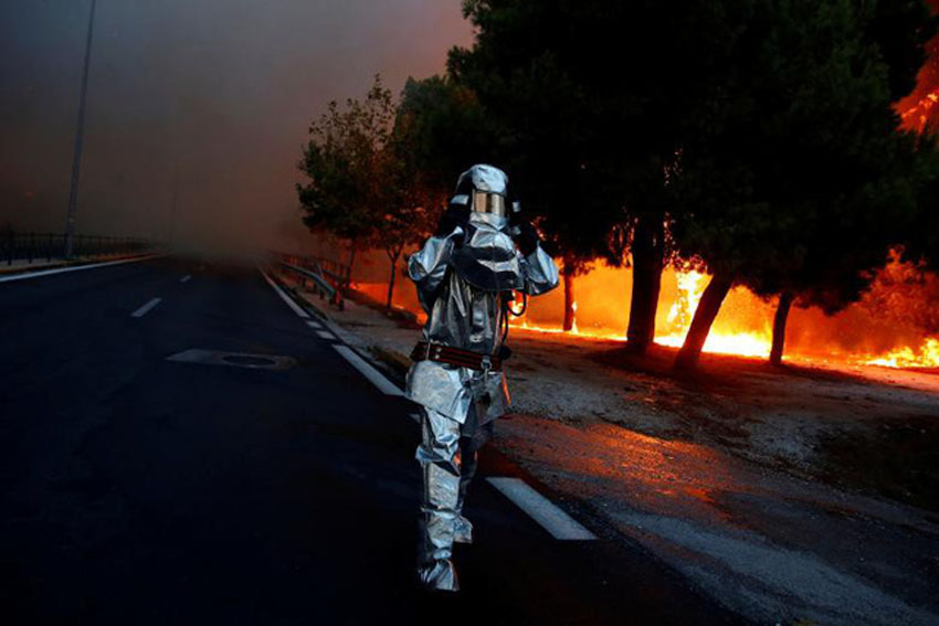 Lính cứu hỏa mặc đồ chống cháy trong khi cháy rừng lan ra thị trấn Rafina, gần Athens, Hy Lạp, hôm 23/7.