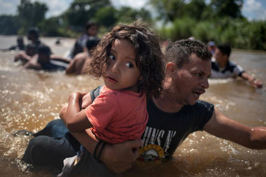 Luis Acosta giữ bé gái Angel Jesus, 5 tuổi, khi đoàn người di cư vượt sông Suchiate từ Guatemala sang Mexico hôm 29/10. Acosta và Jesus đều là người Honduras. Họ đang trên đường từ Trung Mỹ đến Mỹ.