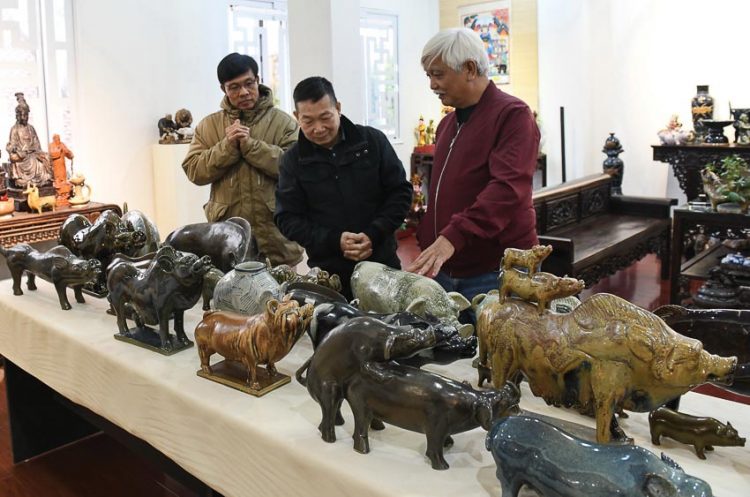 Nhà sử học Dương Trung Quốc (bìa phải) với các tượng lợn trong bộ sưu tập của ông