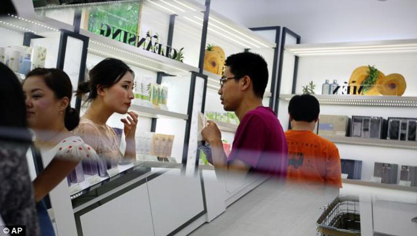 Nữ nhân viên một cửa hàng mỹ phẩm tư vấn sản phẩm cho khách hàng nam giới