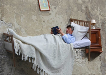 Nghệ sĩ Thierry Mandon đọc sách trên vách từơng tòa nhà bỏ hoang