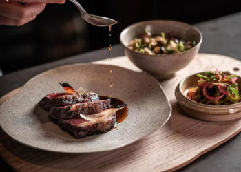 Bàn ăn tinh tế tại Miên Saigon với món khai vị từ hoa dại và dưa gang, trong không gian mùa hè ấm cúng.