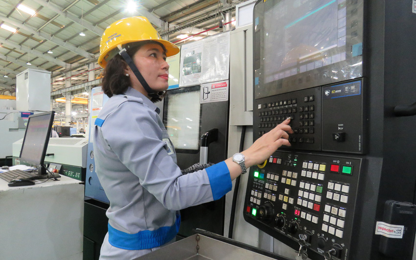 Chị Dương Thị Ánh, công nhân vận hành máy tiện CNC, tổ hợp cơ khí thao tác trên bảng điều khiển máy tiện CNC.