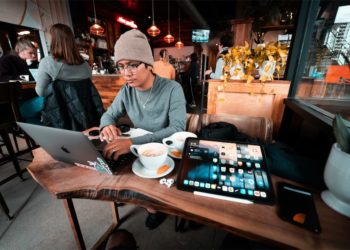Bạn trẻ Gen Z Việt Nam làm việc trên laptop tại quán cà phê, ánh đèn ấm.