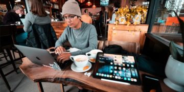 Bạn trẻ Gen Z Việt Nam làm việc trên laptop tại quán cà phê, ánh đèn ấm.