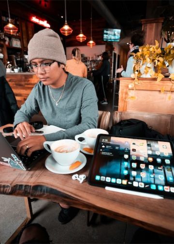 Bạn trẻ Gen Z Việt Nam làm việc trên laptop tại quán cà phê, ánh đèn ấm.