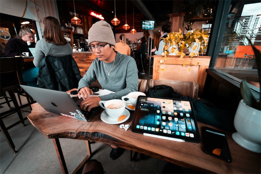 Bạn trẻ Gen Z Việt Nam làm việc trên laptop tại quán cà phê, ánh đèn ấm.