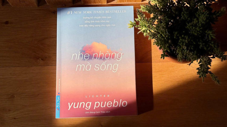 Bìa sách “Nhẹ nhàng mà sống” của Diego Perez (Yung Pueblo) đặt cạnh tách trà sáng trong ánh nắng nhẹ – biểu tượng của sự an yên và tự tại.